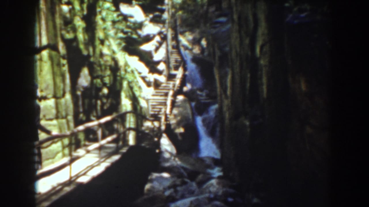 Cliffside walkway and railings lead toward a waterfall in Mount Washington, New Hampshire, on 8mm home-movie film.