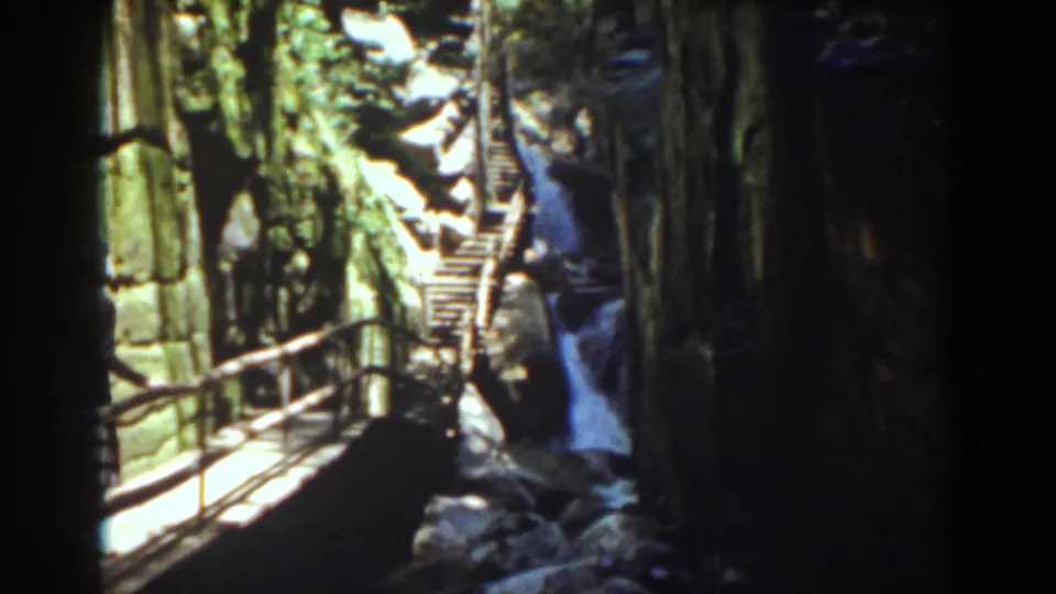 Cliffside walkway and railings lead toward a waterfall in Mount Washington, New Hampshire, on 8mm home-movie film.