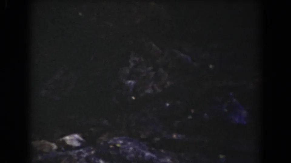 Late frame from the Mount Washington clip showing shadowed rock, rough stones, and the upper sign area mostly cropped out.