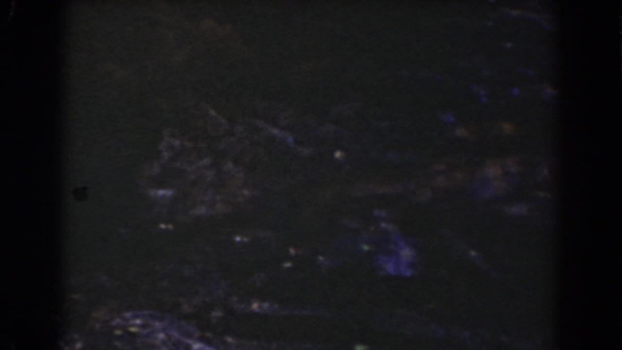 1939 Mount Washington home-movie frame showing dark stones and subdued water reflections in a shadowed stream view.