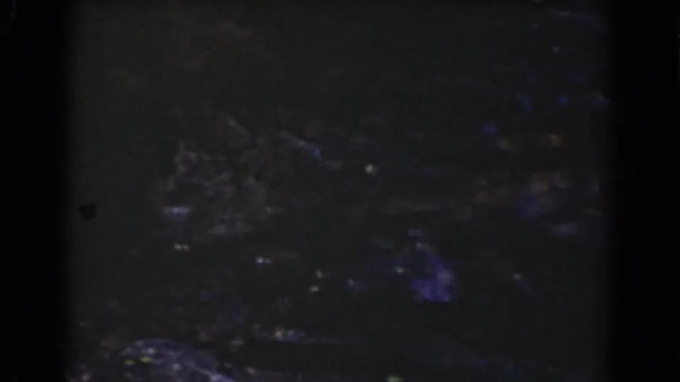 1939 Mount Washington home-movie frame showing dark stones and subdued water reflections in a shadowed stream view.