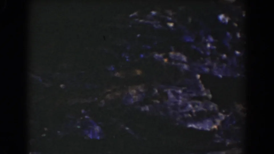 Vintage 8mm frame from Mount Washington showing dark rugged stones and small water highlights across the stream bed.