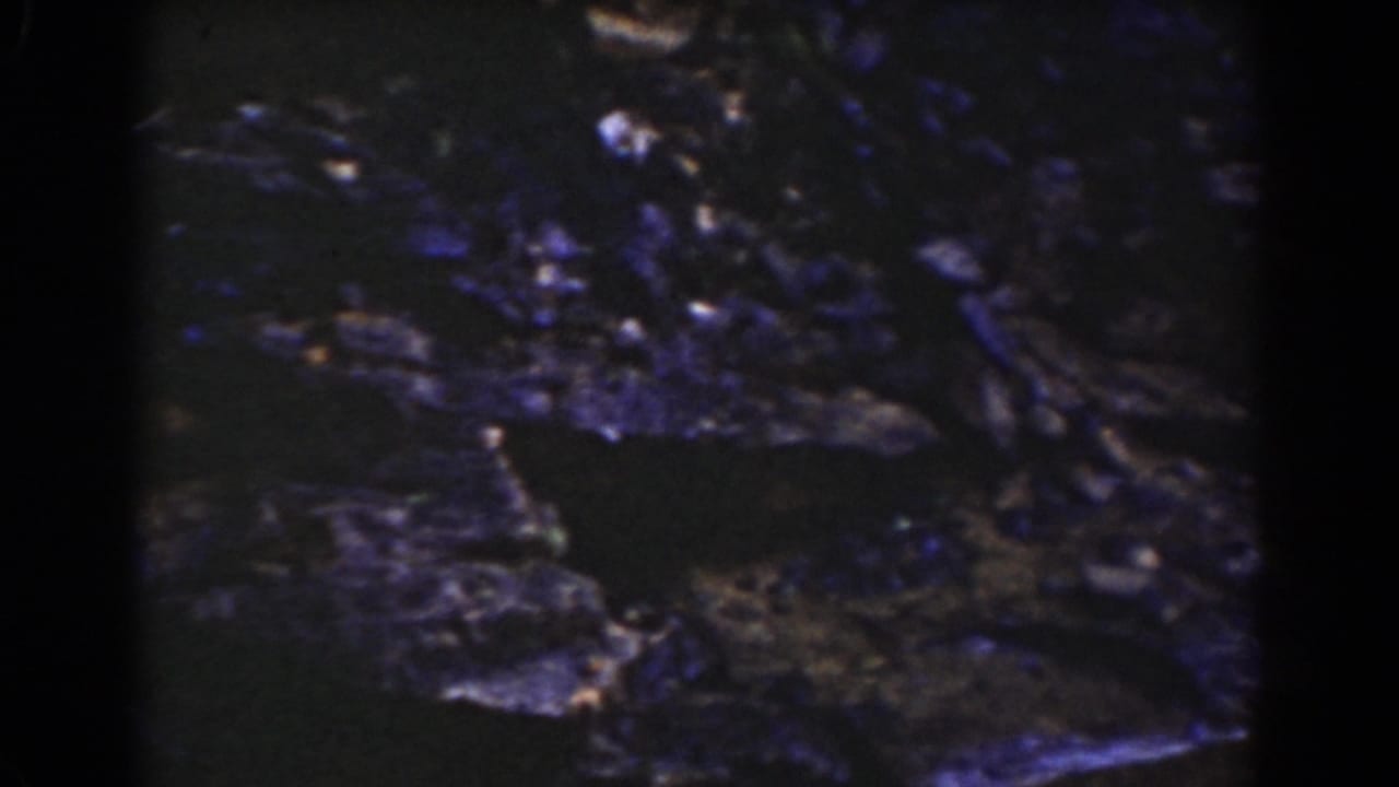 1939 New Hampshire mountain footage showing flowing water crossing dark rock, with bright reflections and blue color drift from aged film.