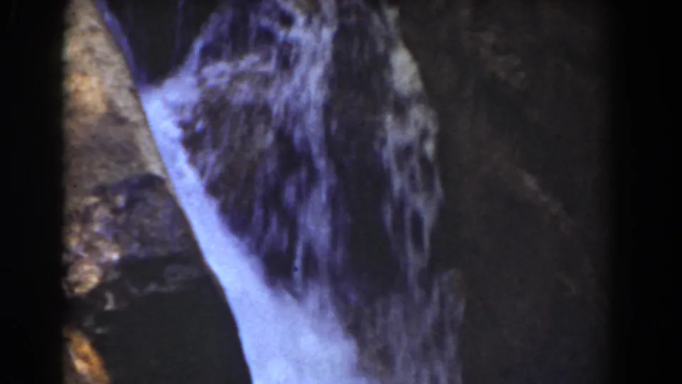 Close 1939 Mount Washington home-movie frame showing pale water moving over dark, textured rock.