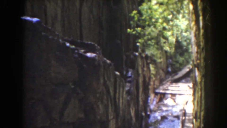 1939 Mount Washington home-movie view of a narrow forest channel with textured walls and bright water or walkway in the distance.