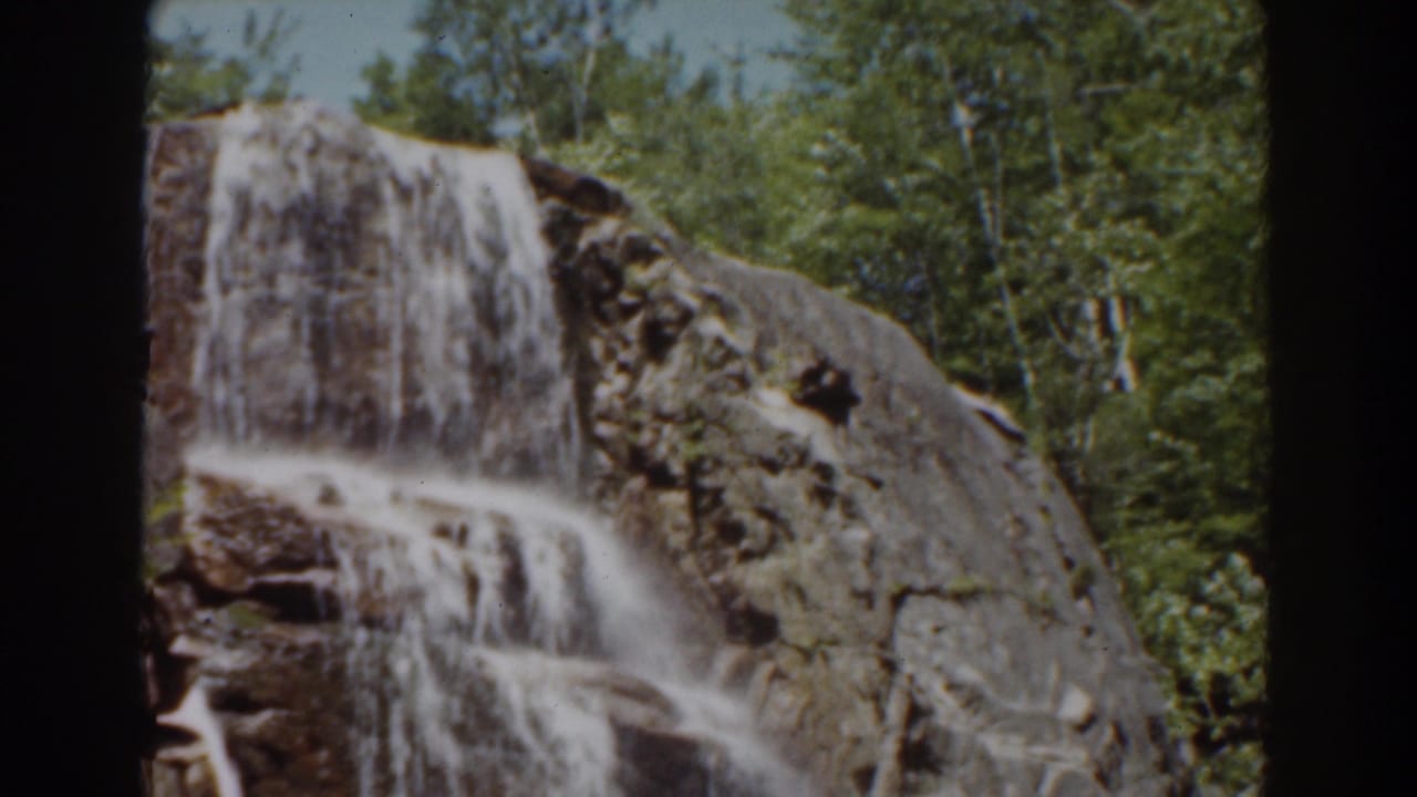 A 1939 New Hampshire waterfall view, with white water crossing brown stone and trees visible above the rocks.