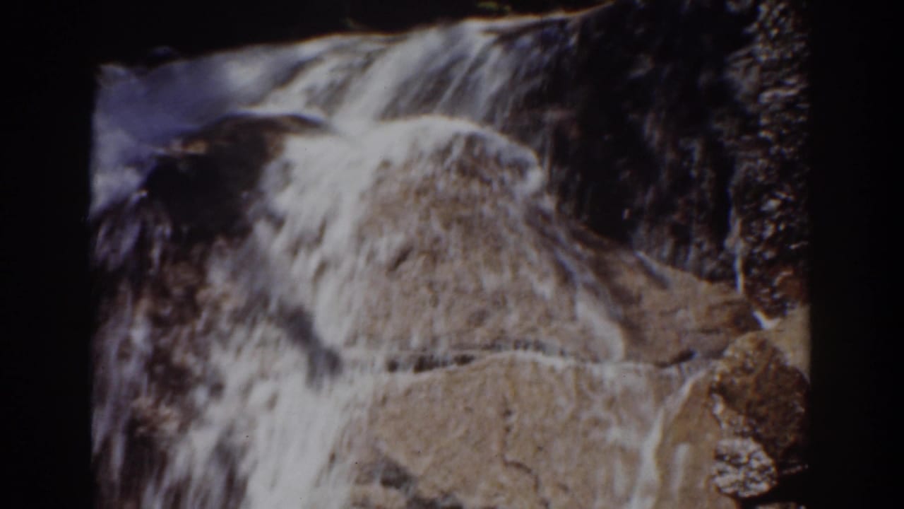 Closer 8mm view of water rushing down stepped brown rocks, likely within the Mount Washington waterfall scene.