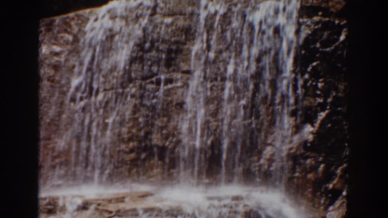 Vertical sheet of waterfall descending over a dark brown rock face in the supplied Mount Washington 1939 home-movie clip.