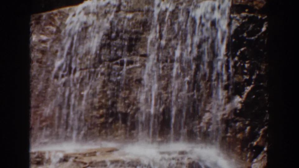Vertical sheet of waterfall descending over a dark brown rock face in the supplied Mount Washington 1939 home-movie clip.