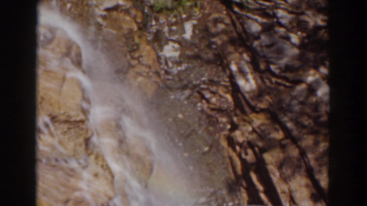 1939 8mm frame from Mount Washington showing white water running over textured rock and shadowed cracks.