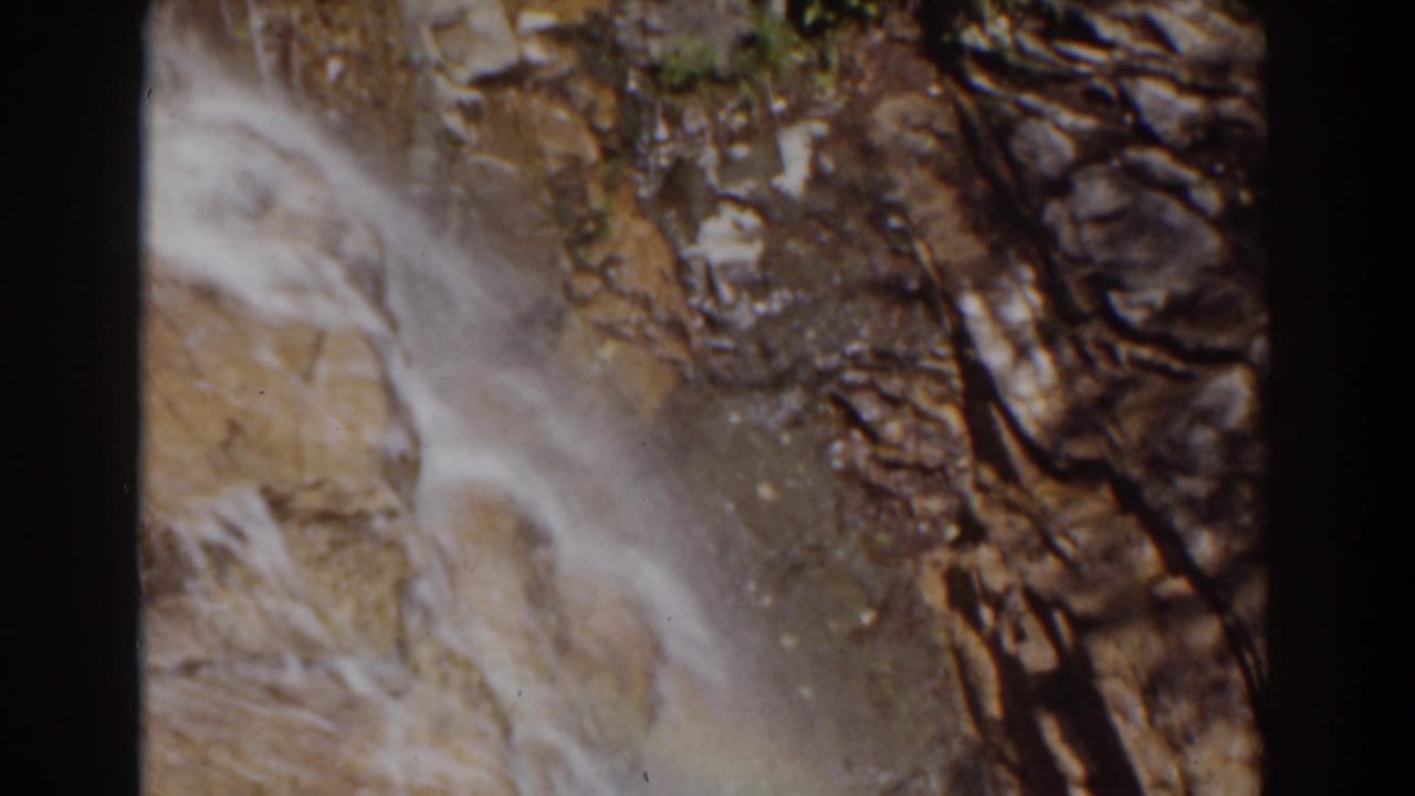 1939 Mount Washington 8mm frame showing blurred water flow across rugged rock with dark vertical fractures.