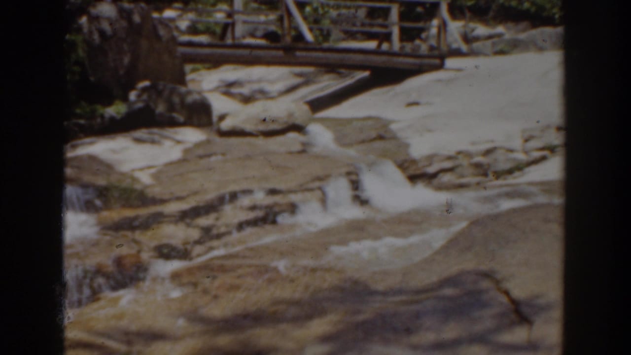 Mount Washington 8mm footage shows a rocky stream below a wooden bridge, with bright highlights and faded color from the film scan.