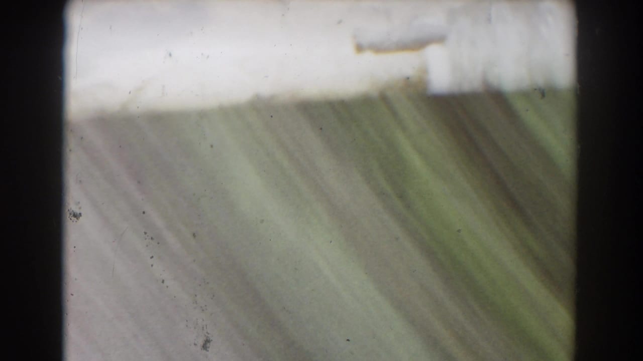 Soft, abstract end frame from the 1939 Mount Washington stream shot, with greenish water or wet stone and visible film dust.