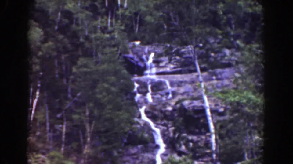 Mount Washington waterfall framed by trees and rock ledges in a faded 1939 8mm home-movie view.