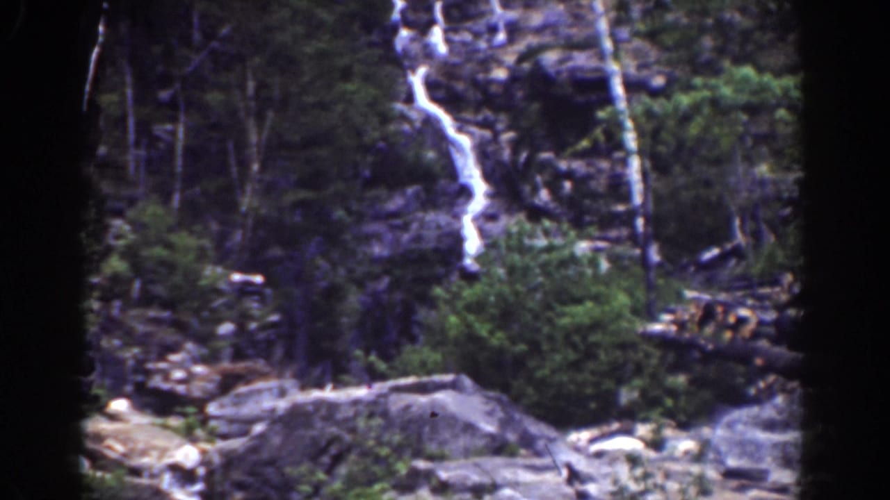 1939 Mount Washington home-movie frame showing a narrow waterfall on a rocky forested slope with visible 8mm film borders.
