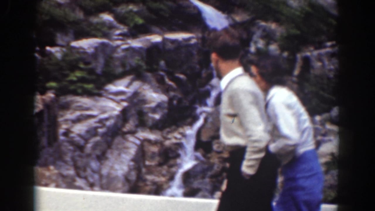 Two adult visitors cross the foreground at a Mount Washington-area waterfall overlook in 1939 8mm footage.