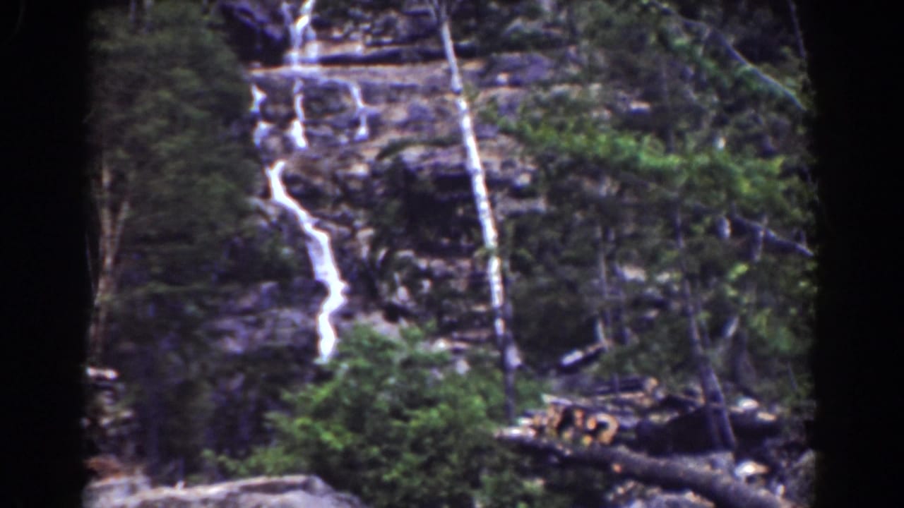 A repeated view of Silver Cascade, with white water cutting down rocky ledges behind trees in 1939 8mm footage.