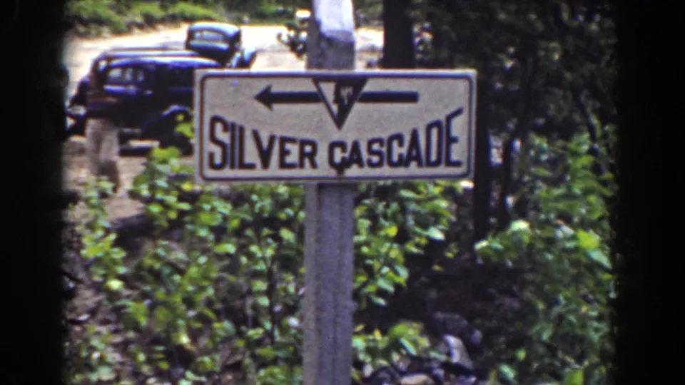 A roadside sign reading Silver Cascade stands near parked vintage automobiles in Mount Washington, New Hampshire.