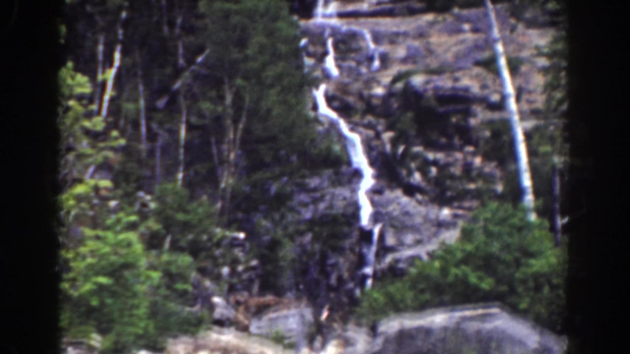 1939 Mount Washington footage frames Silver Cascade from a distance, showing water over rocky ledges and surrounding forest.