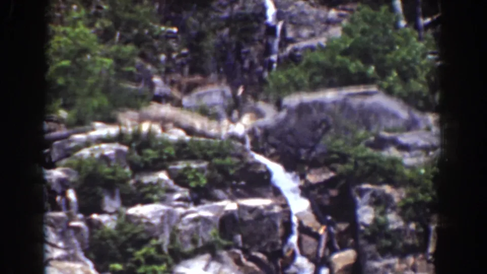 Mount Washington waterfall scene on 8mm film, with water moving through a rocky channel below forest growth.
