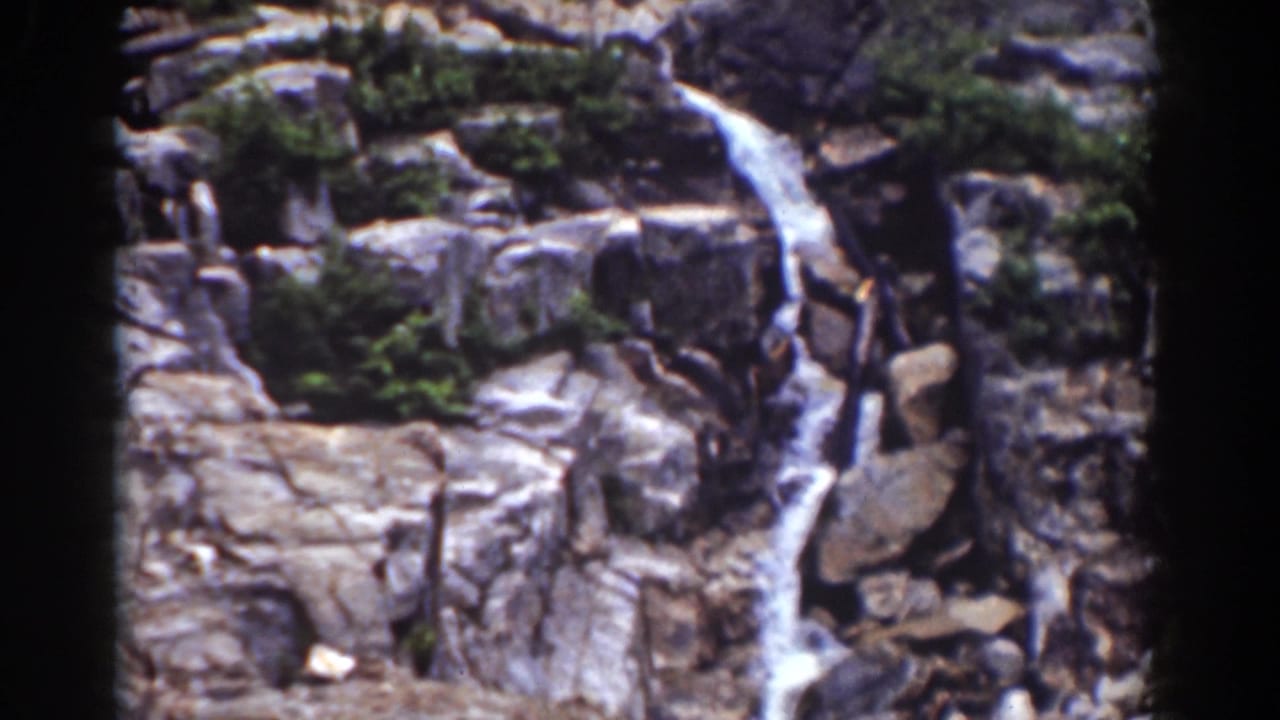 1939 New Hampshire home-movie view of cascading water crossing boulders and ledges in a forested mountain area.