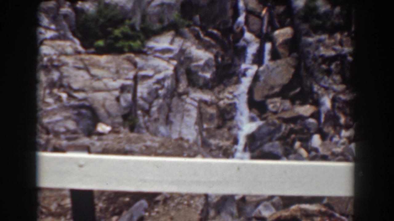 Final Mount Washington frame with a rocky waterfall partly viewed behind a pale foreground rail and dark 8mm edges.