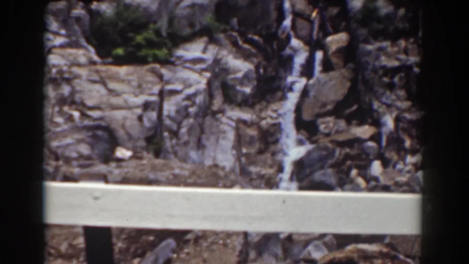 Final Mount Washington frame with a rocky waterfall partly viewed behind a pale foreground rail and dark 8mm edges.