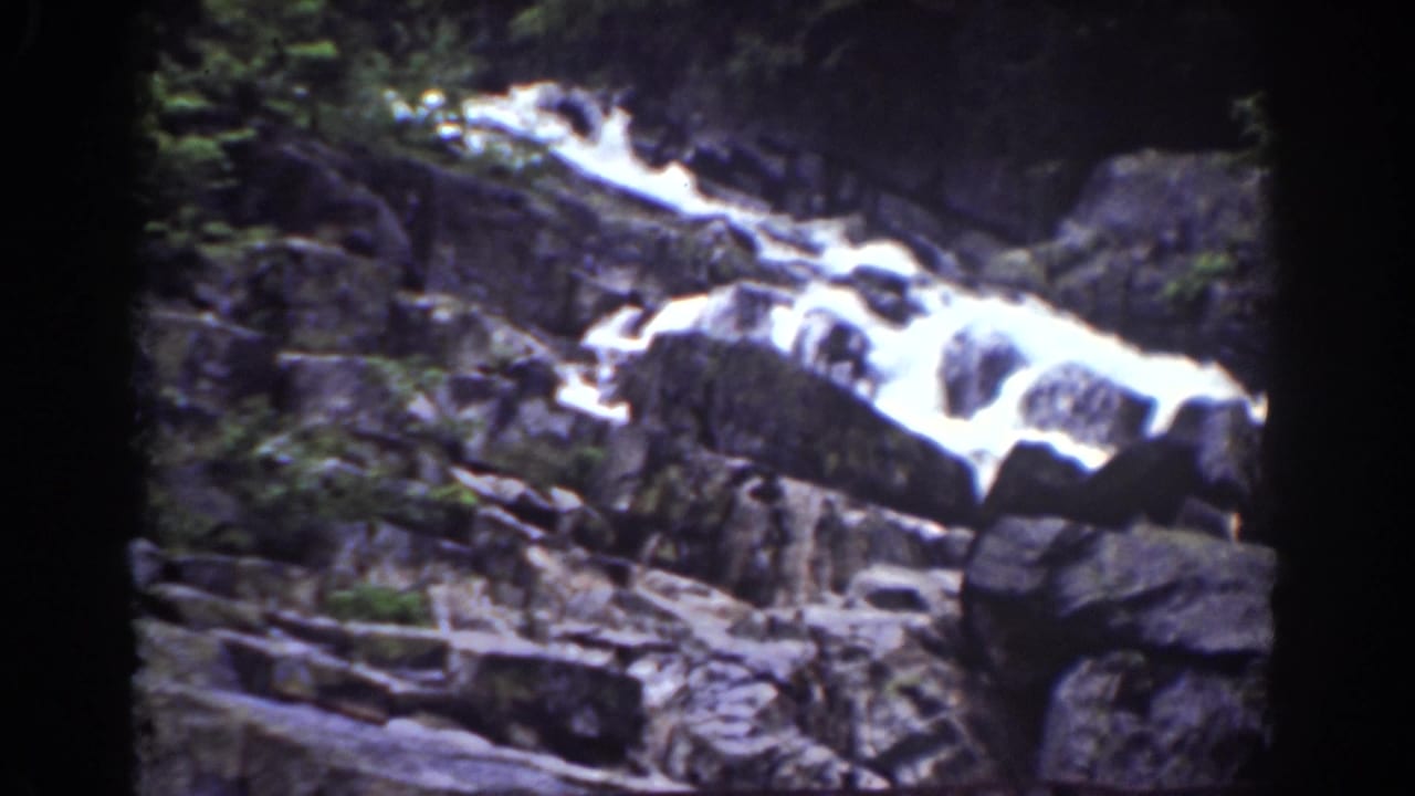 1939 Mount Washington waterfall view with white water spilling over layered rocks and rough forest debris below.