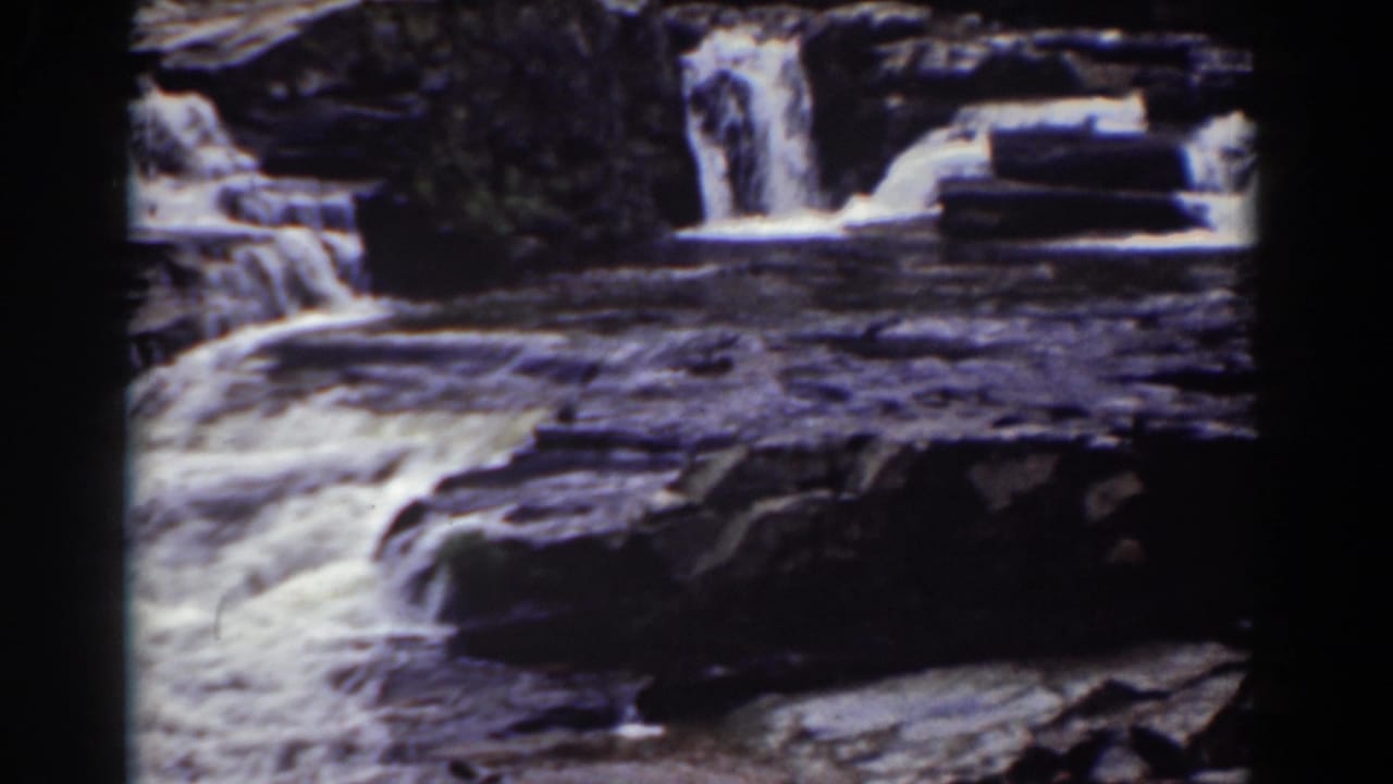 Vintage 8mm frame of a Mount Washington cascade, with white water crossing dark rock and a smaller fall in back.