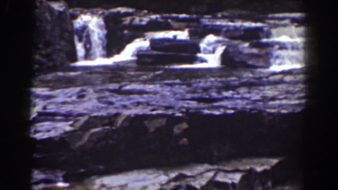 Layered rock ledges with shallow water flowing over small cascades.