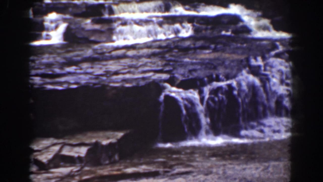 Mount Washington cascade frame showing water spilling over several naturally stepped rock layers in a vintage 8mm view.