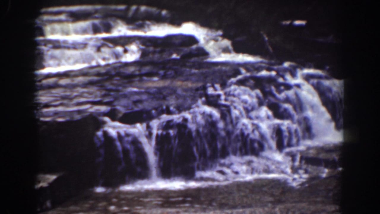 Small New Hampshire waterfall seen in soft 8mm color, with water breaking over stepped rock formations.