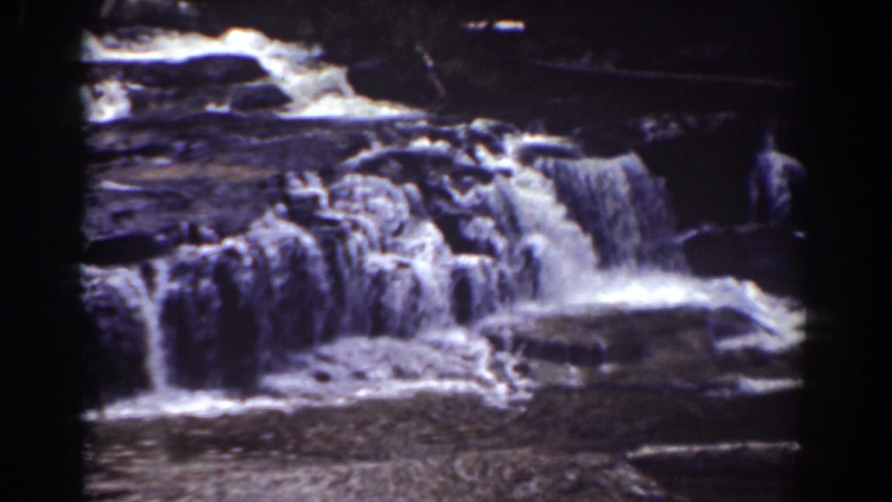 1939 Mount Washington home-movie frame with foamy water running over uneven ledges and pooling below.