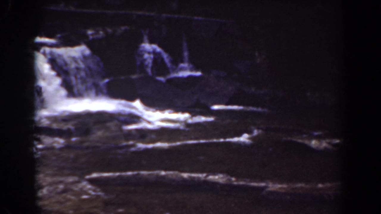 1939 Mount Washington footage shows water running over broad rock ledges beneath dark surrounding trees.