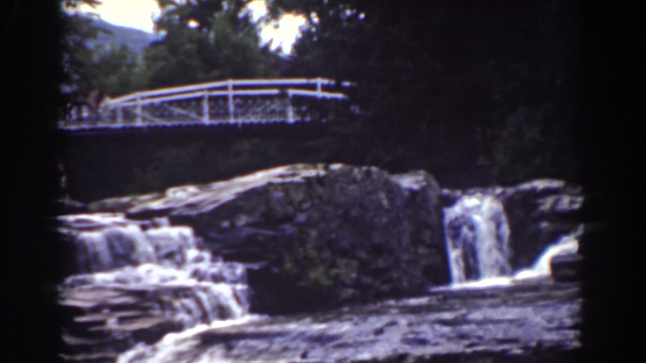 1939 Mount Washington frame showing a white bridge over a rocky cascade, with trees and a faint mountain slope beyond.