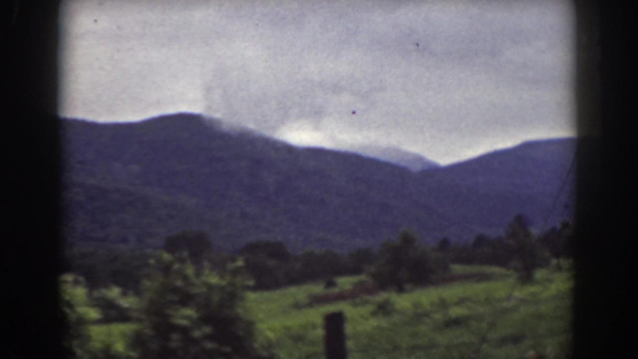 Soft 8mm view of New Hampshire countryside near Mount Washington, with fields and mountains under gray clouds.