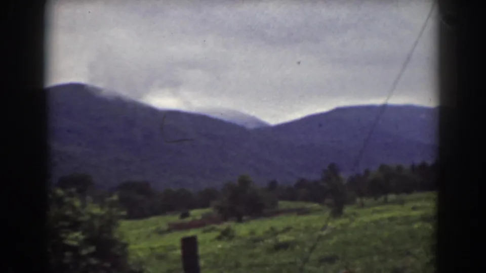 1939 Mount Washington, New Hampshire 8mm frame showing pasture, a fence post, trees, and distant blue mountain ridges.