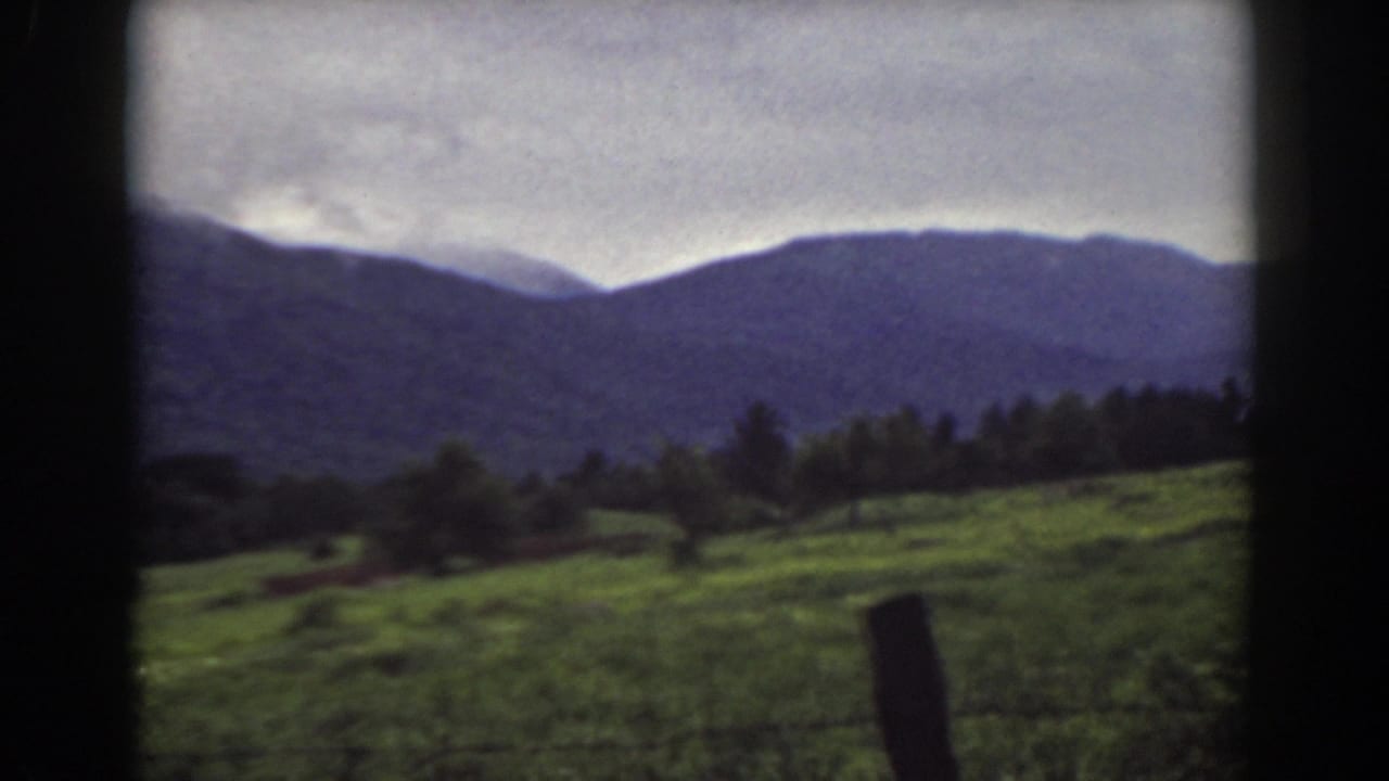 1939 Mount Washington, New Hampshire frame showing a grassy slope, scattered trees, a fence post, and distant mountains.