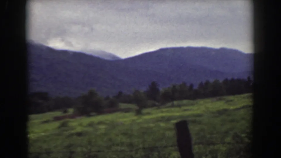 1939 Mount Washington, New Hampshire frame showing a grassy slope, scattered trees, a fence post, and distant mountains.