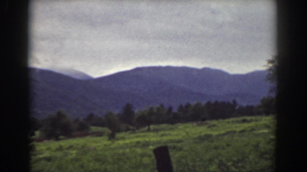 1939 Mount Washington, New Hampshire 8mm frame with pasture, foreground fence post, tree line, and muted mountain ridge.