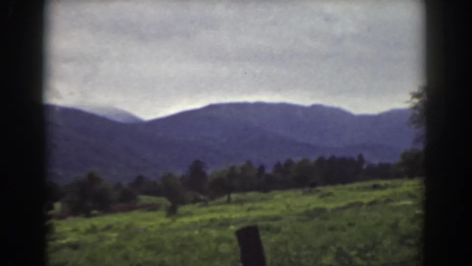 1939 Mount Washington, New Hampshire 8mm frame with pasture, foreground fence post, tree line, and muted mountain ridge.