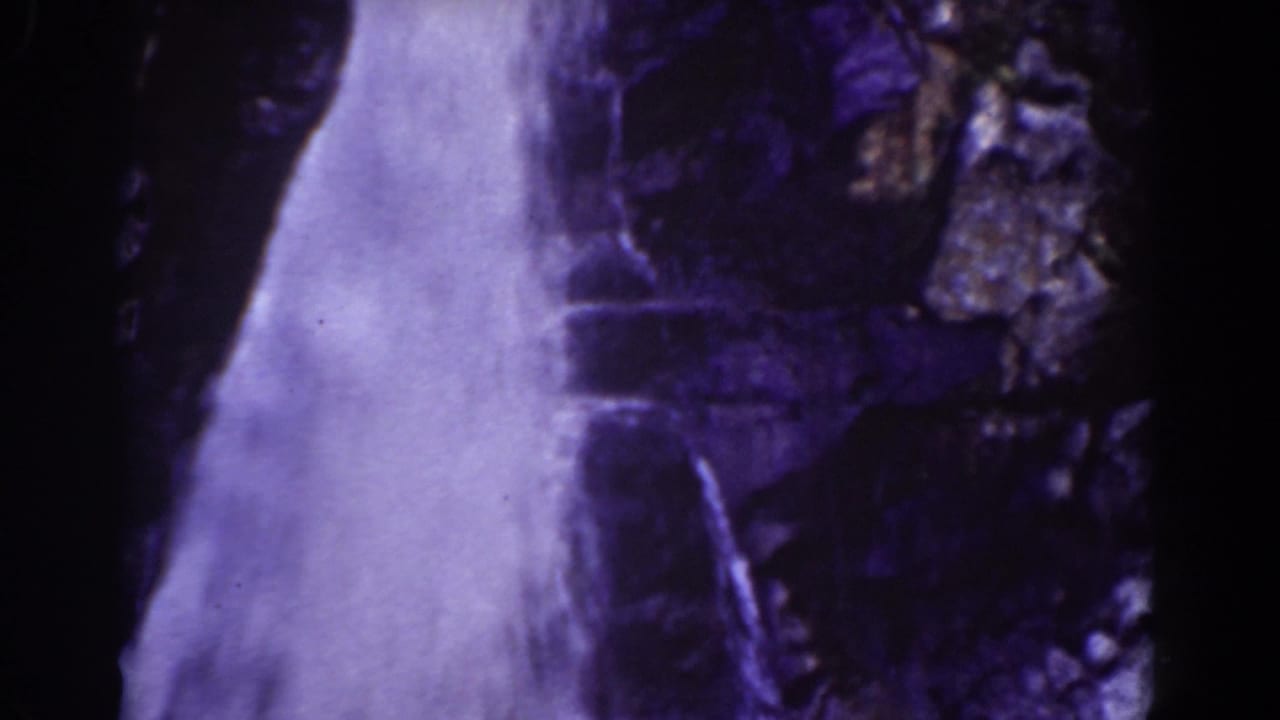 White cascade falling along a rocky wall with heavy blue-purple tint.