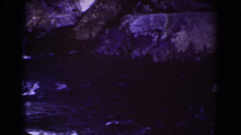 1939 Mount Washington frame with the waterfall partly at right, dark pooled water, and rough rock surfaces in low light.