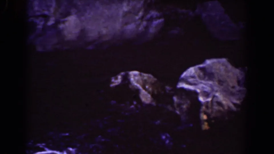 A Mount Washington rocky watercourse appears in a dim 1939 8mm frame, with pale stones, dark pools, and heavy blue-purple color cast.