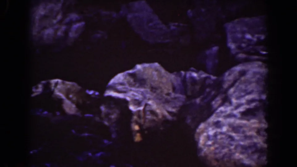 Close view of Mount Washington rocky terrain, with shallow water, large rounded stones, and dense shadow in a 1939 8mm home-movie frame.