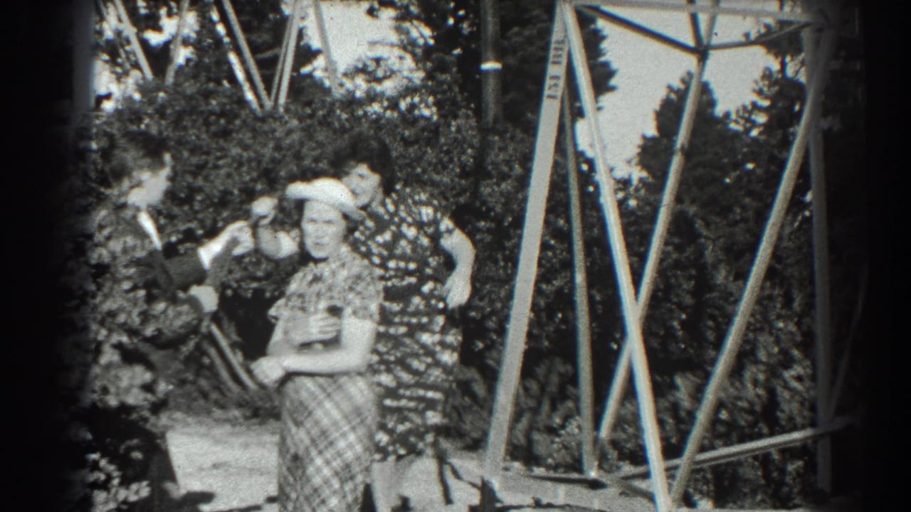 In 1939 San Francisco home-movie footage, a suited man playfully points a prop gun while two women in patterned dresses stand nearby.