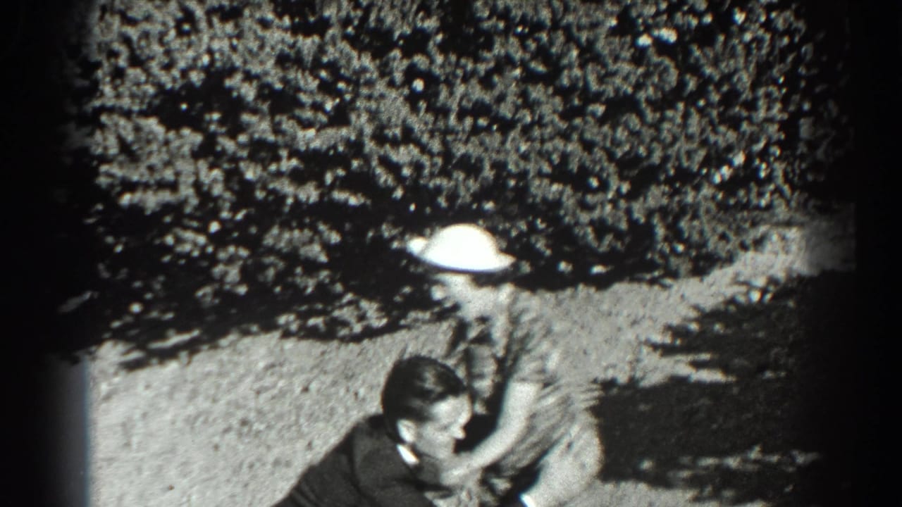 Woman in a plaid dress runs toward a man on a sunlit hillside.