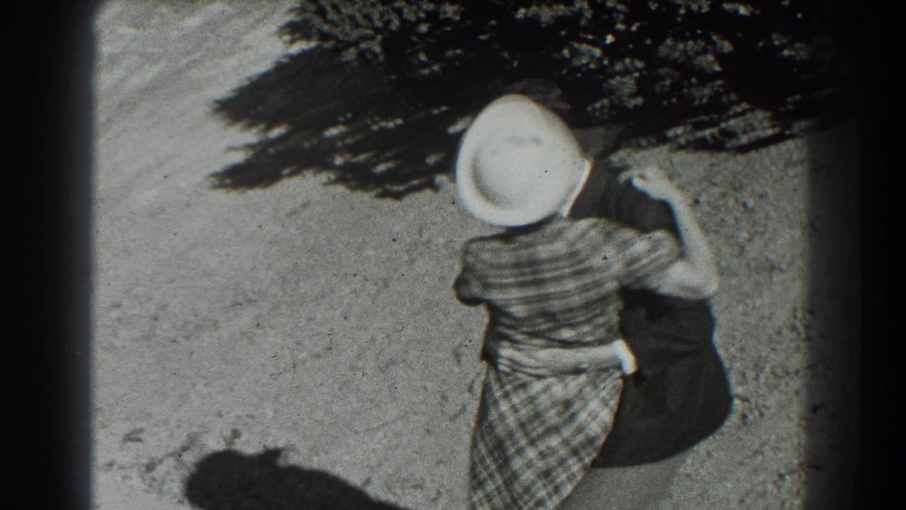 Woman in a white hat moves downhill with one arm raised.