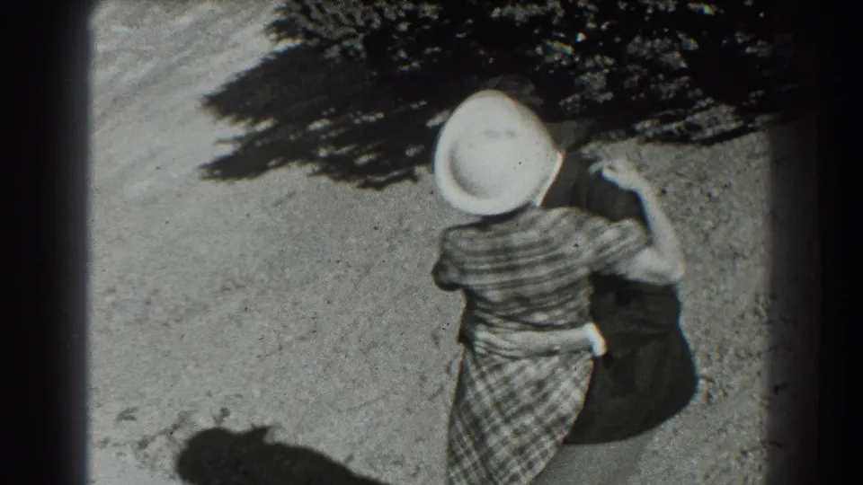 The woman in a plaid dress and white hat moves across the hillside, seen from above in the 1939 San Francisco home movie.