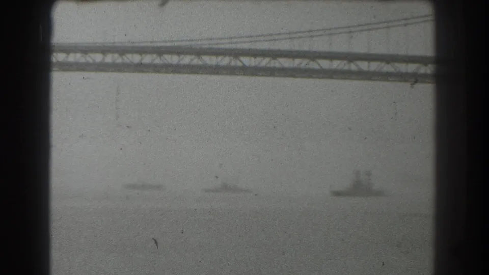 San Francisco bay view from 1939 showing the bridge structure overhead, hazy water, and a distant ship near the right side of the frame.